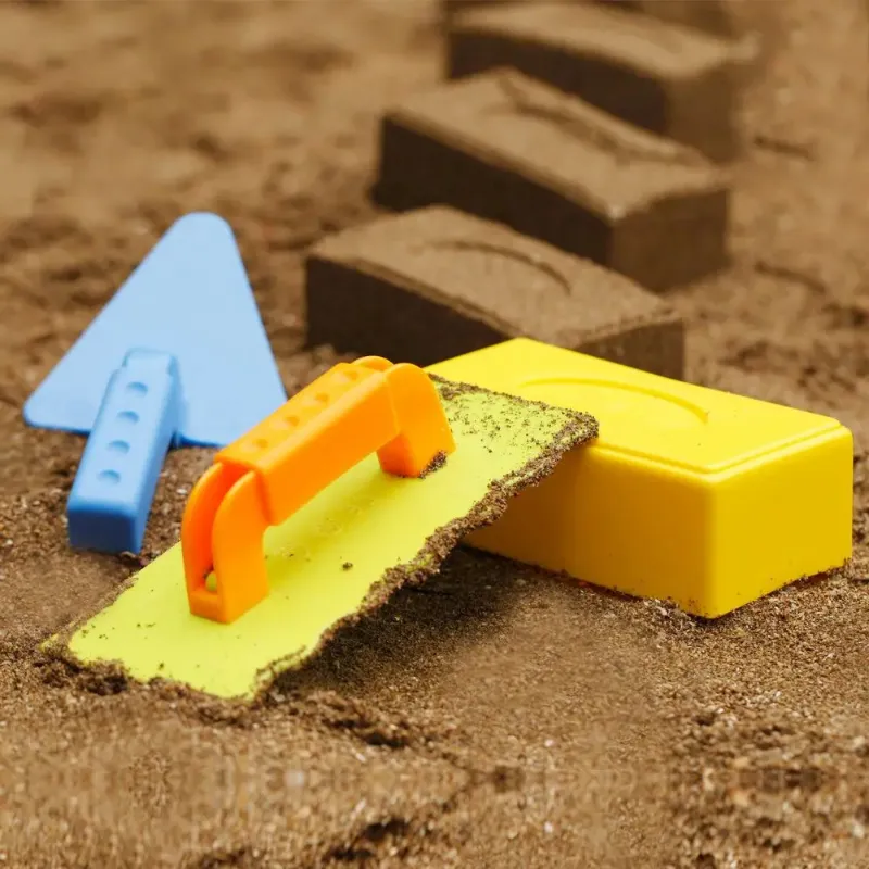 Snow brick maker set in action, creating structured snow formations on a sandy surface.
