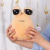 Cozy alien plush toy pillow with large, expressive eyes and a minimalist face, held gently in someone's hands.