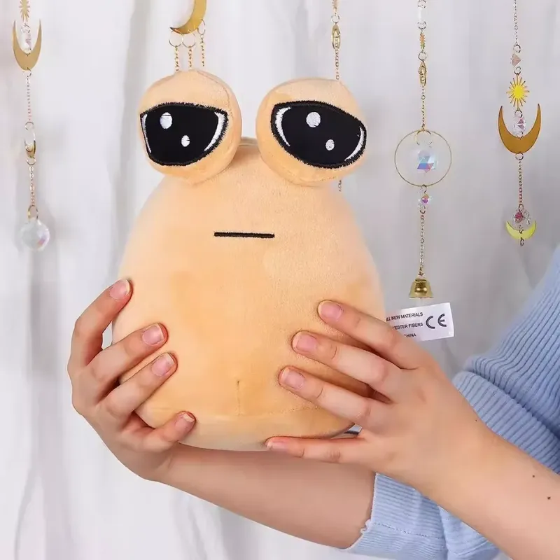 Cozy alien plush toy pillow with large, expressive eyes and a minimalist face, held gently in someone's hands.