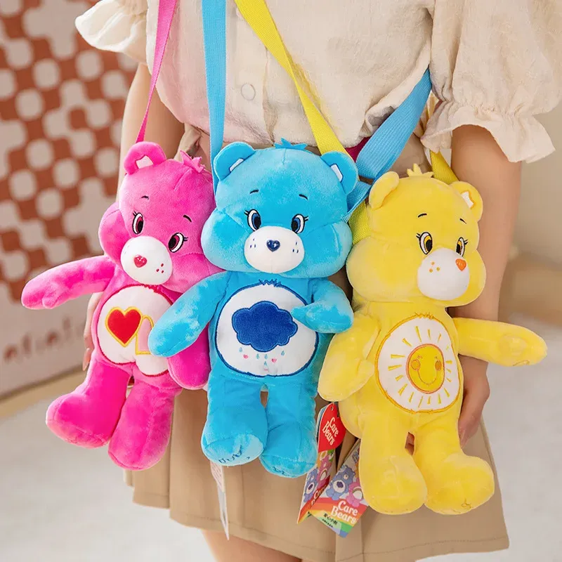 A child showcasing three Care Bears plush backpacks in pink, blue, and yellow.