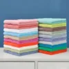 Two stacks of Cotton Hand Towels Set in assorted colors, placed side by side on a countertop.