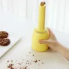 Hand holding a yellow desktop vacuum cleaner while cleaning crumbs.