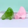 Close-up view of green and pink heart-shaped Gua Sha face massagers.