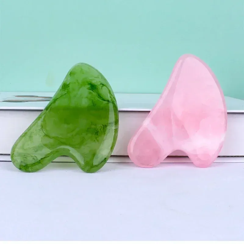 Close-up view of green and pink heart-shaped Gua Sha face massagers.
