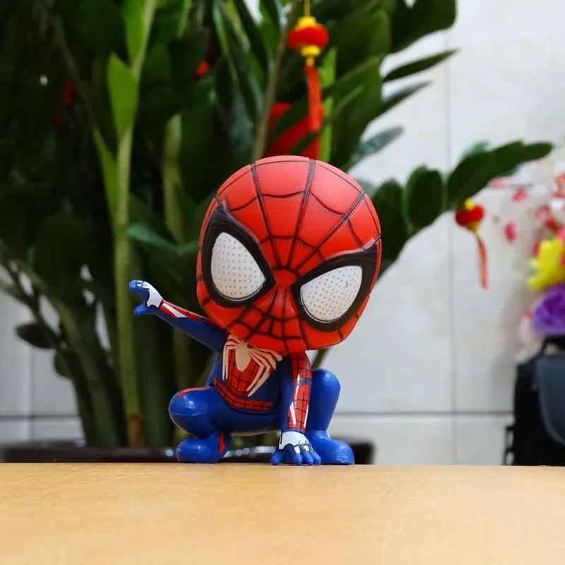 Spider-Man Action Figure standing confidently on a wooden table with a decorative plant in the background.