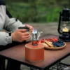 Ultralight portable camping stove with a bright flame, perfect for outdoor cooking.