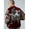 A person wearing a red baseball uniform coat with elaborate dragon and floral embroidery on the back.