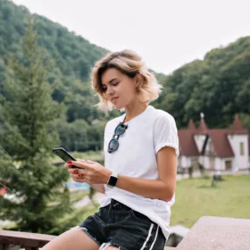 nice girl lean back to the edge of the stairs and working with her smartphone