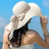 Woman wearing FAITOLAGI straw hat at beach with sunset